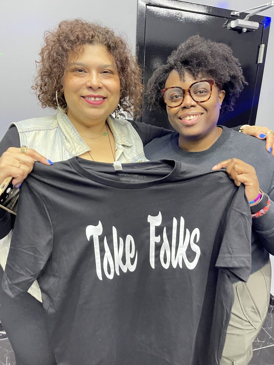 Two friends holding up a black Toke Folks tee