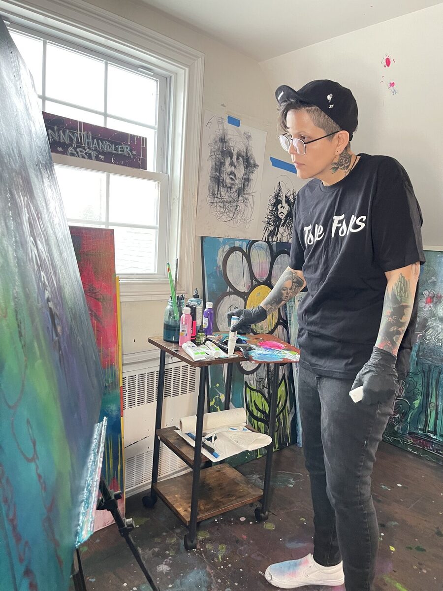 An artist in a Toke Folks tee painting in the studio